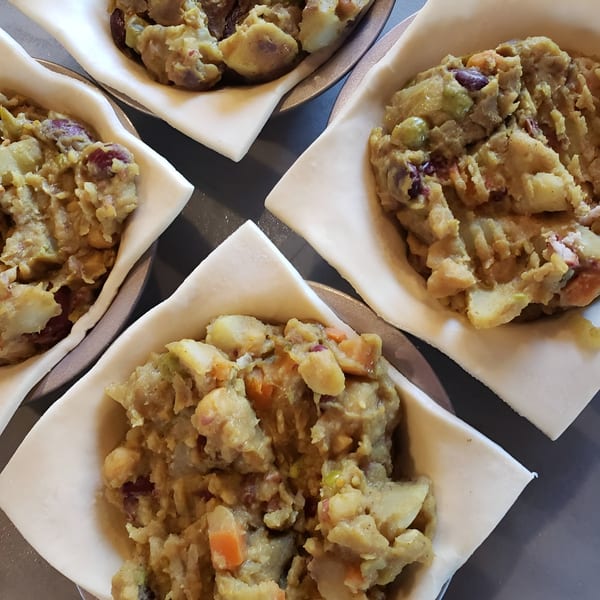 Four uncooked Bula Pies Fiji pastries filled with a savory potato and vegetable mixture.