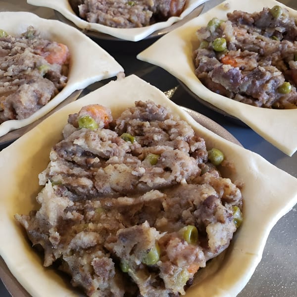 Four Bula Pies Fiji pastries with savory meat and vegetable filling in uncooked crusts.